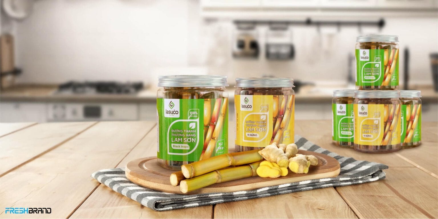 A jar of Lasuco sugar sticks beside sugarcane and ginger