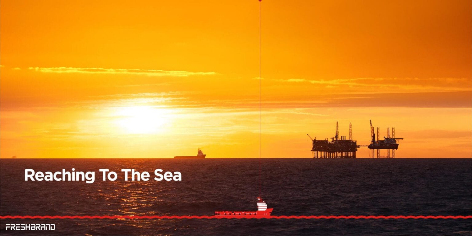 The tagline Reaching To The Sea, with a drilling rig at sunset